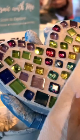 Hands holding a colorful mosaic heart with vibrant glass tiles