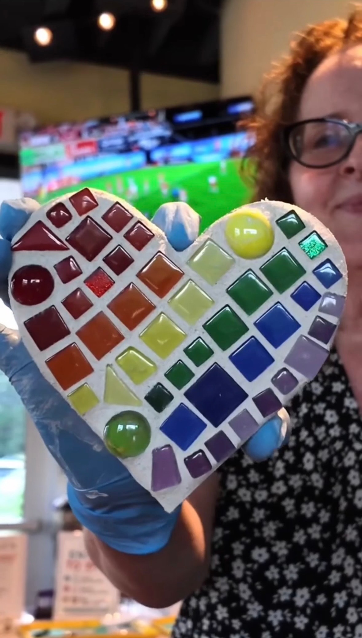 The Creative Teachair holding a completed rainbow mosaic heart